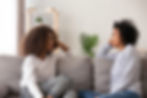 Parent talking to their teen as they sit on couch