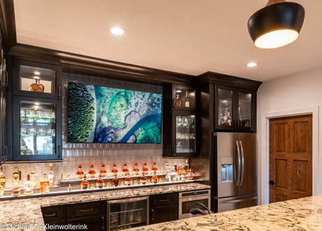 Custom home bar with glass cabinets, stone countertops and LED backlighting by Lake Lumber.