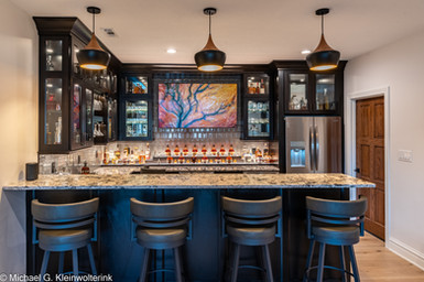 Custom home bar with glass cabinets, stone countertops and LED backlighting by Lake Lumber.