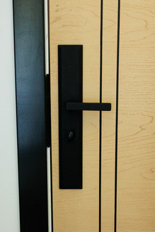 Matte black modern door hardware on custom wood entry door installed by Lake Lumber.