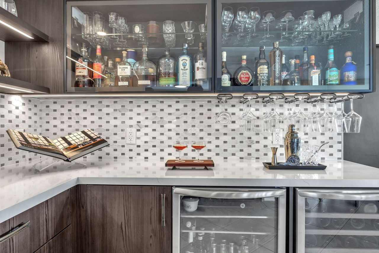 Custom wet bar with glass-front cabinetry, a mosaic backsplash and beverage refrigerators in Mary Beth and Gerry’s home.
