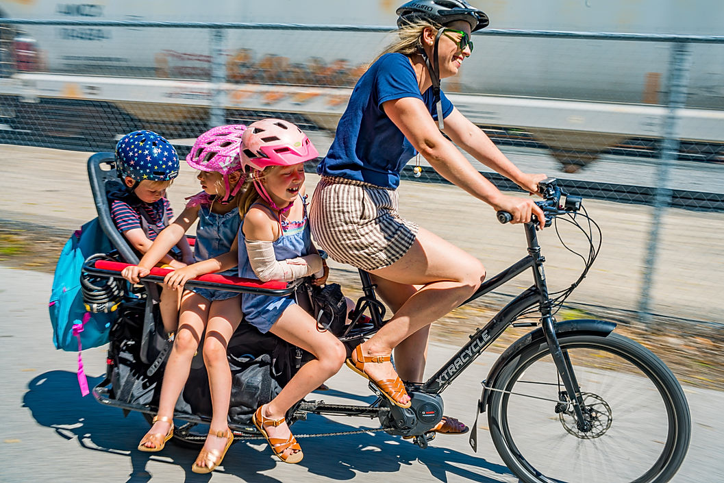 Mom biking with three kids in the back