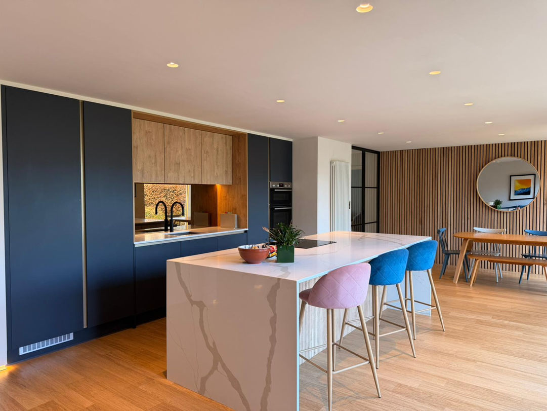 Modern open plan kitchen in Caldy Wirral with indigo blue cabinets, oak island and Calacatta Gold quartz worktops