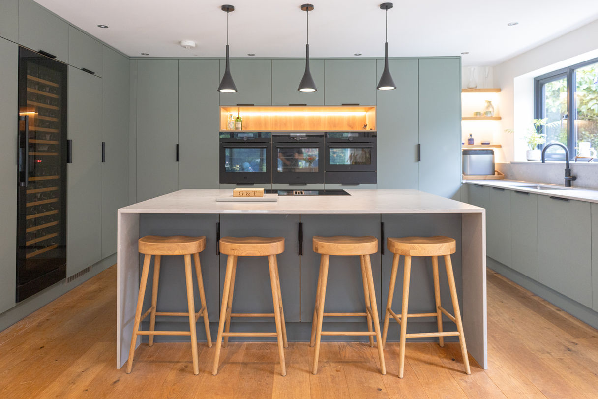 Modern family kitchen in Cuddington Cheshire with green cabinets, quartz worktops and oak flooring