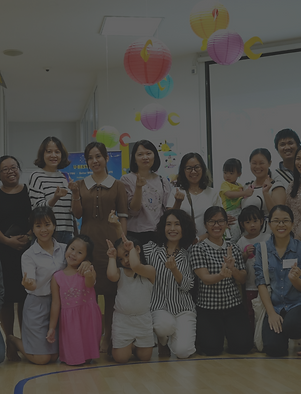 Trainer, ba mẹ và các con đang đứng chụp lưu niệm cùng nhau trong lớp học