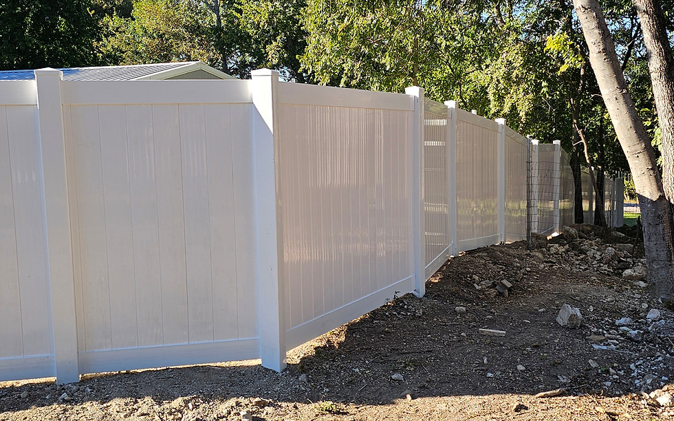 White vinyl privacy fence installed along wooded residential property line
