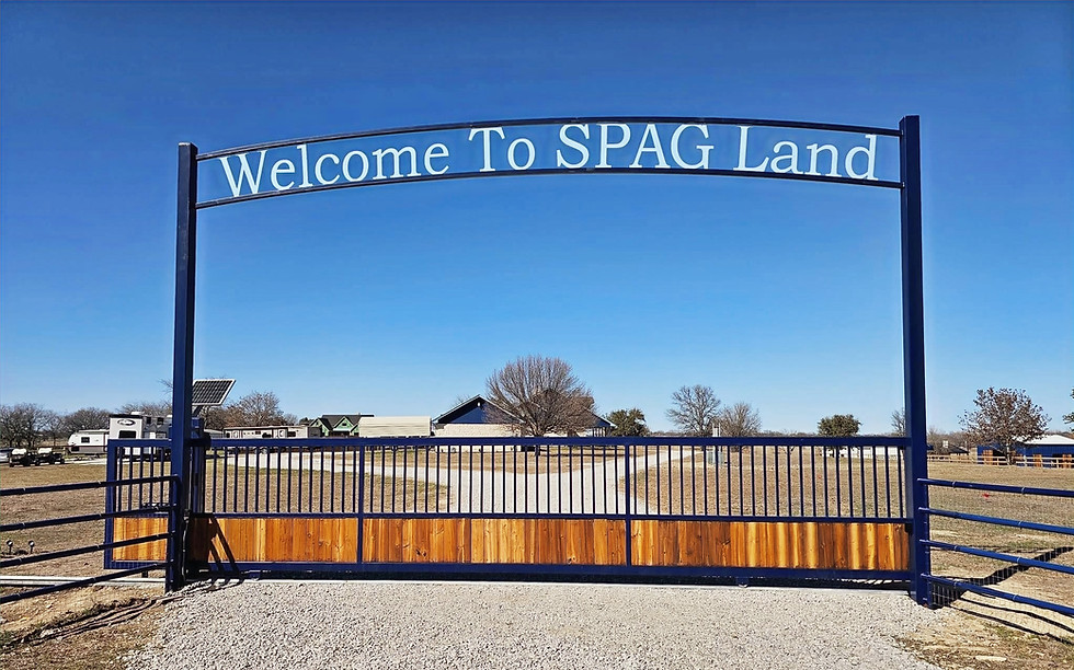 Custom ranch entry slide gate with metal frame and cedar wood panels reading Welcome To SPAG Land