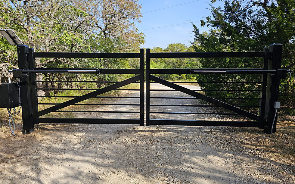Custom black metal double swing gate with automatic opener on rural driveway