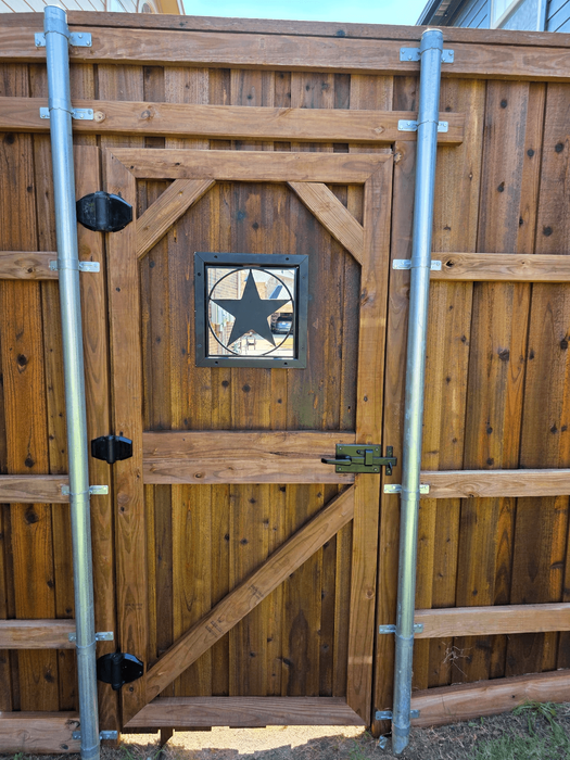 Interior custom wood pedestrian gate with medium-stained vertical pickets, horizontal and diagonal bracing, decorative square star insert, and black metal hardware integrated into a privacy fence.