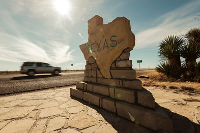 A car speeds along past the Texas border sign from New Mexico near Carlsbad in the USA.jpg