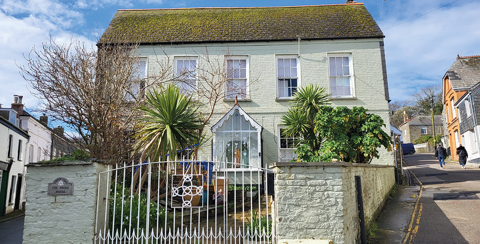 The Cross House, a Grade II listed property in Padstow old town, North Cornwall, positioned on a prominent corner just moments from Padstow Harbour, restaurants and cafés. This substantial period home spans three storeys and retains original features including tall sash windows, high ceilings and wooden floors that reflect its historic character. Interior images show spacious reception rooms filled with natural light, a traditional kitchen and utility area, and seven double bedrooms, six with en suite bathrooms, plus an additional bedroom with private shower room. Outside, the property benefits from a front garden overlooking Padstow and rare off road parking, making it a versatile coastal home in one of Cornwall’s most sought after harbour towns, marketed by Jackie Stanley estate agents.