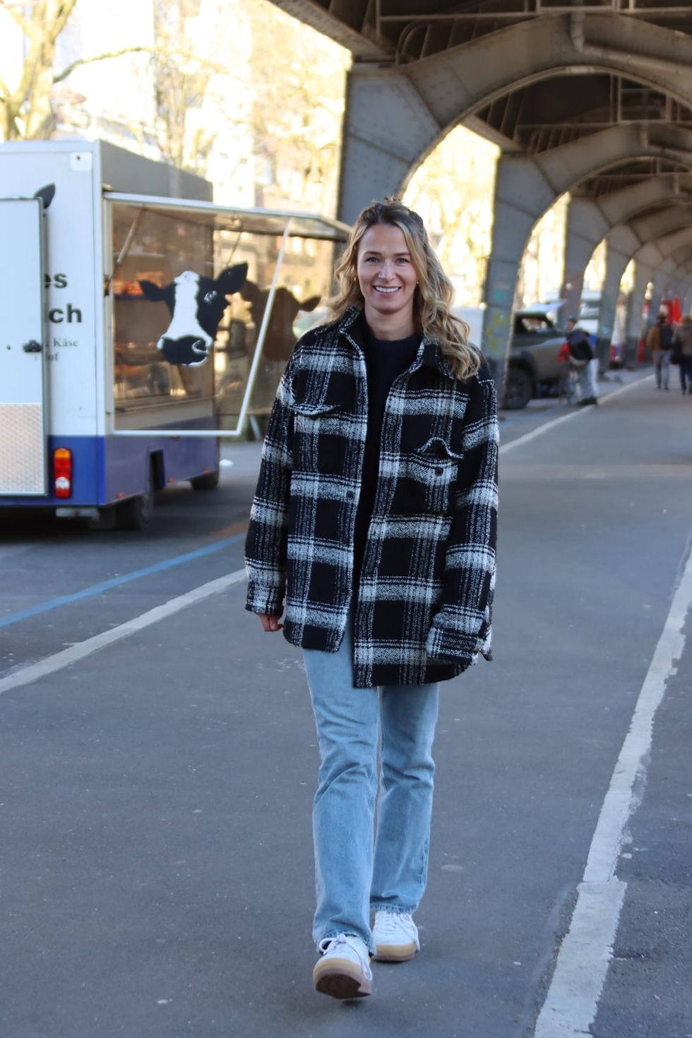 young woman walking under a bridge
