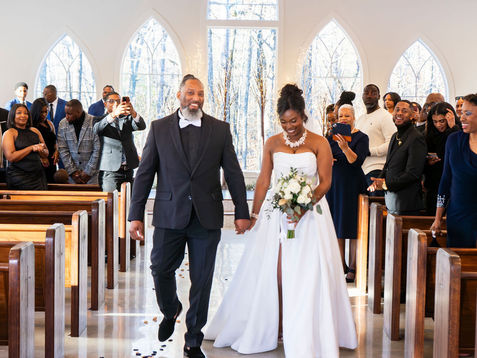 Newlywed couple walking down the aisle, very happy they hired a wedding planner to take care of their big day