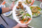 A man holding a plate of grilled sardines, garnished with fresh slices of onion, tomato, and lemon, accompanied by crispy golden potato wedges, creating a hearty and flavorful meal.
