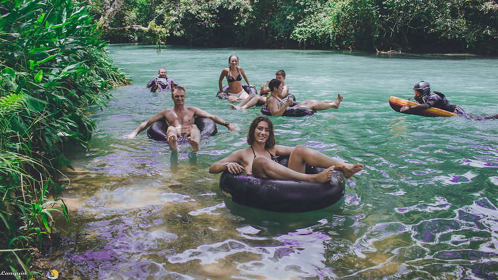Personas haciendo tubing en el río Lanquín con flotadores y vegetación alrededor.