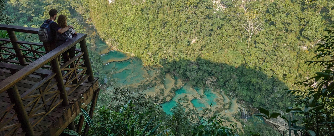 Pareja abrazada en el mirador contemplando las piscinas de Semuc Champey rodeadas de naturaleza.
