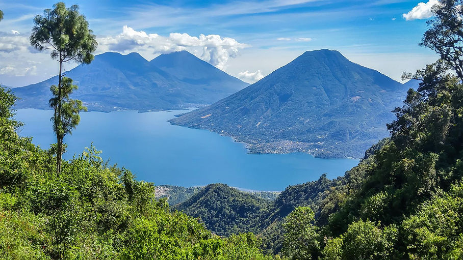 Vista del Lago Atitlán con sus volcanes y montañas reflejados en el agua.
