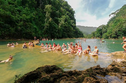 Visitors relaxing in the famous turquoise limestone pools of Semuc Champey surrounded by jungle in A