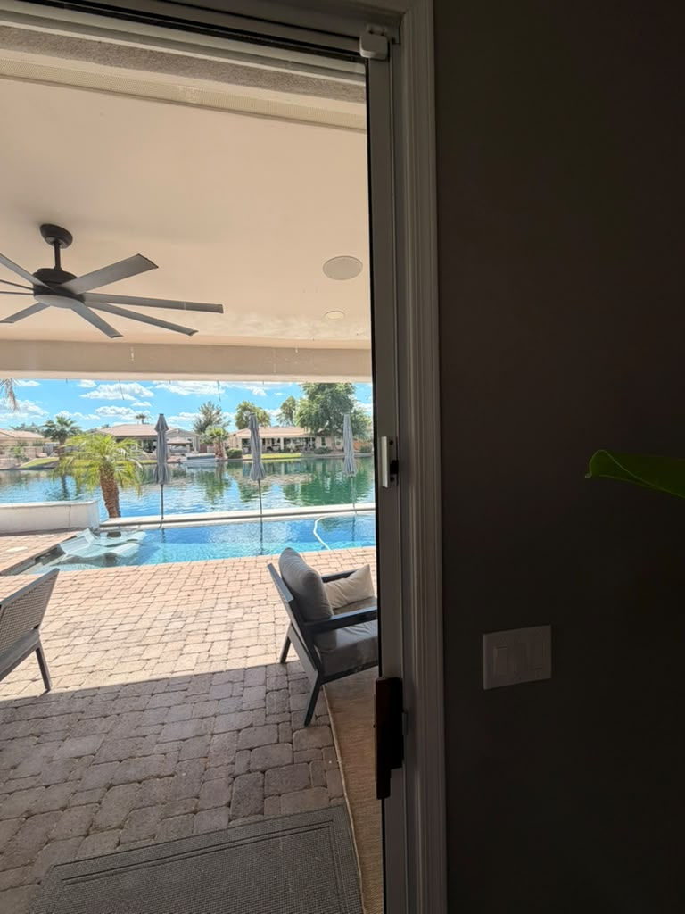 High safety latch mounted at the top of a sliding patio door, out of children's reach, overlooking a backyard pool in Arizona