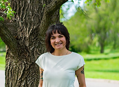 Cincinnati trauma therapist smiling and standing in front of a tree.