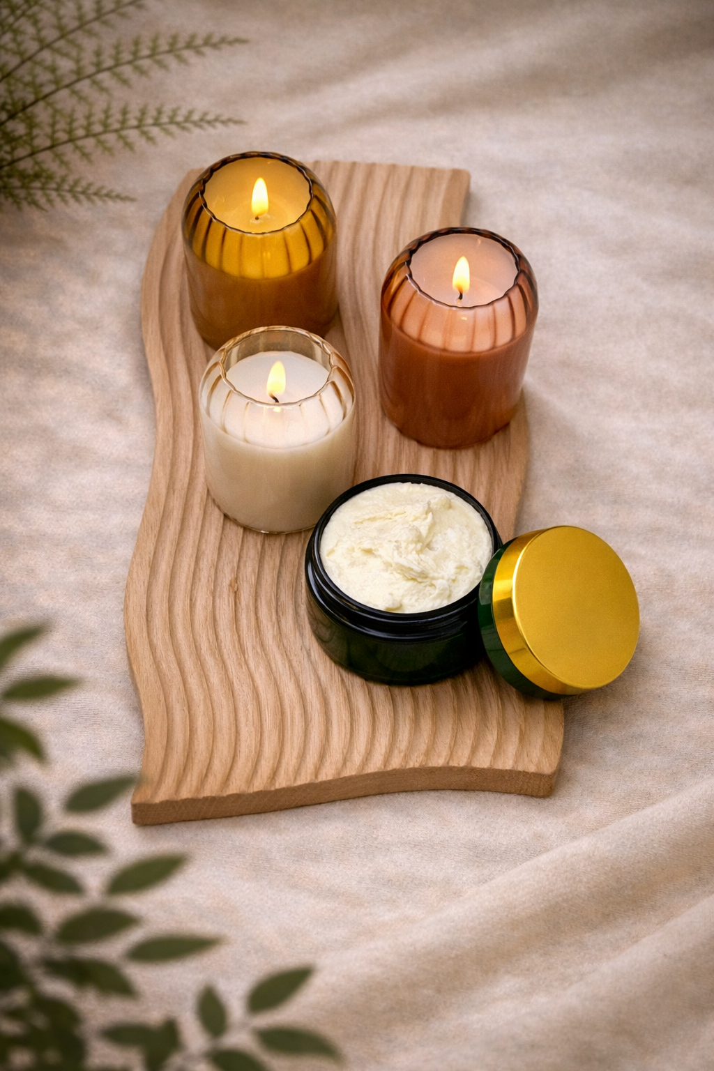 Rooted Gentleman beard and body butter in green jar with gold lid beside lit amber candles on a natural wood tray.