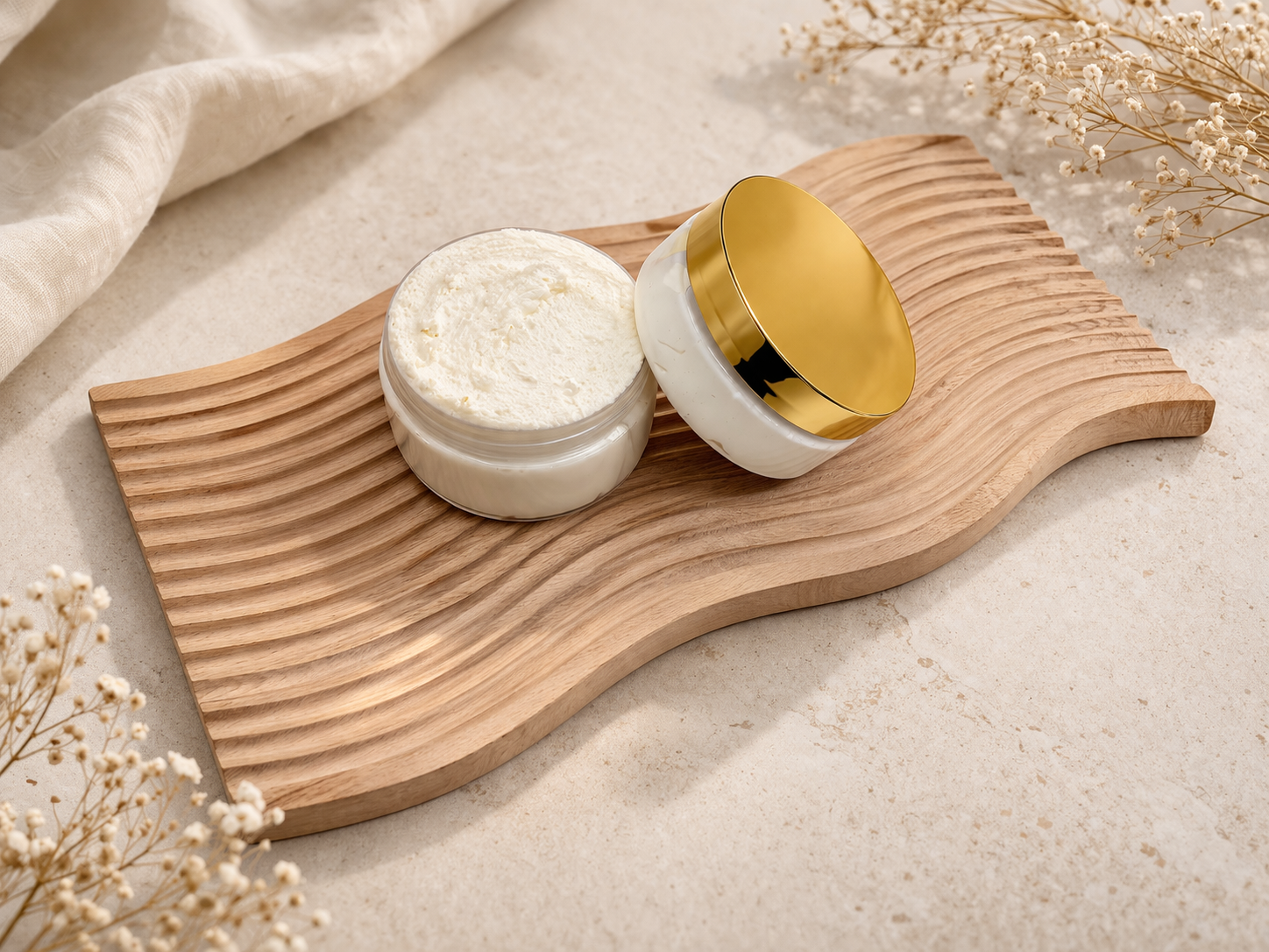 Cashmere Crème whipped body butter in a clear jar with gold lid on a natural wood tray with soft neutral styling.