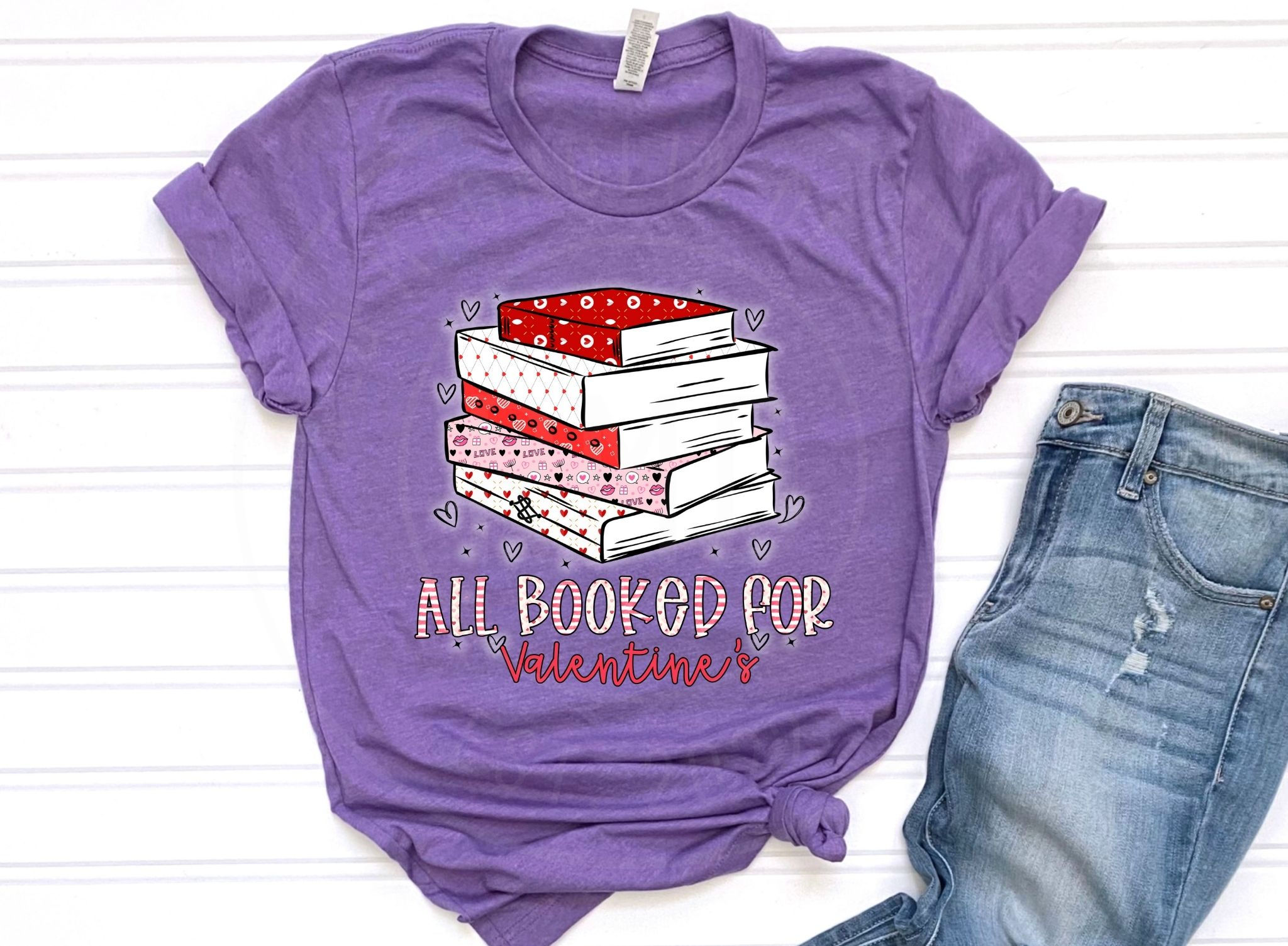 Purple Valentine’s Day shirt with stacked books and “All Booked for Valentine’s” text styled with jeans.
