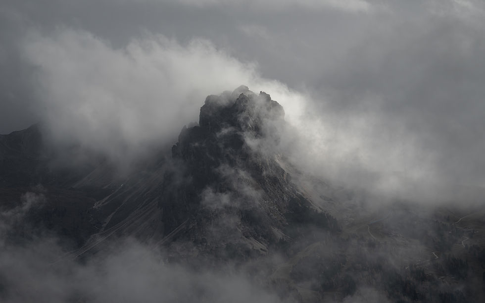 Black and white photo of a jagged mountain peak in the Dolomites with mist flowing around the summit