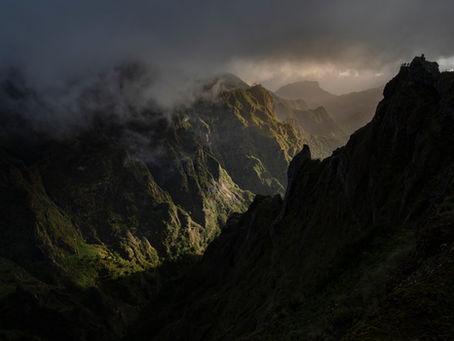 Sunrise light breaking through a dark mountain valley near Pico do Arieiro in Madeira.
