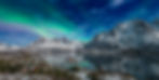The northern lights over a fjord with snow-capped mountains in Lofoten Norway