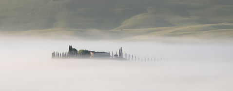 Mist surrounding the villa of Poggio Covili, taken from a distance just after sunrise in Val d'Orcia, Tuscany