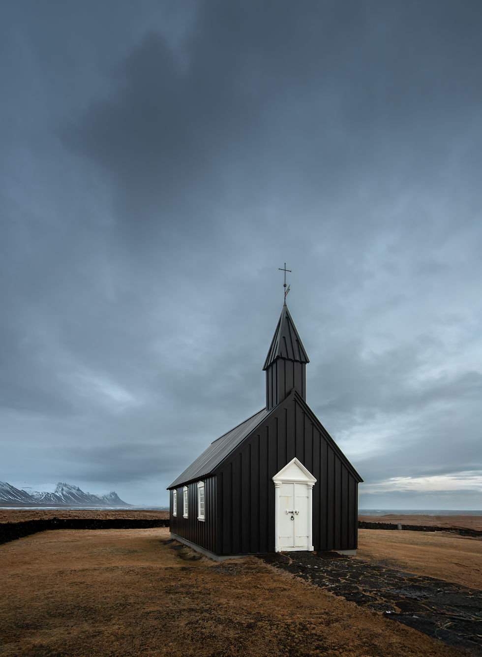 A minimalist composition of Búðakirkja in Iceland, with a dark moody sky of textured cloud.
