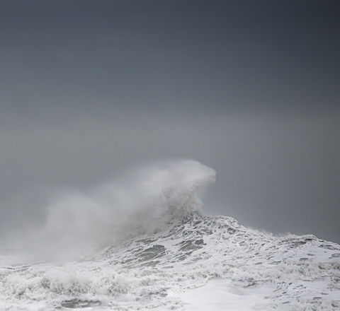 Primo piano drammatico di un’onda con spruzzi nel vento, scattata al largo della costa sud-est dell’Islanda.