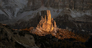 Morning light catching the rocky face of a mountain in the Dolomites, surrouned by shadows and dark rocks.