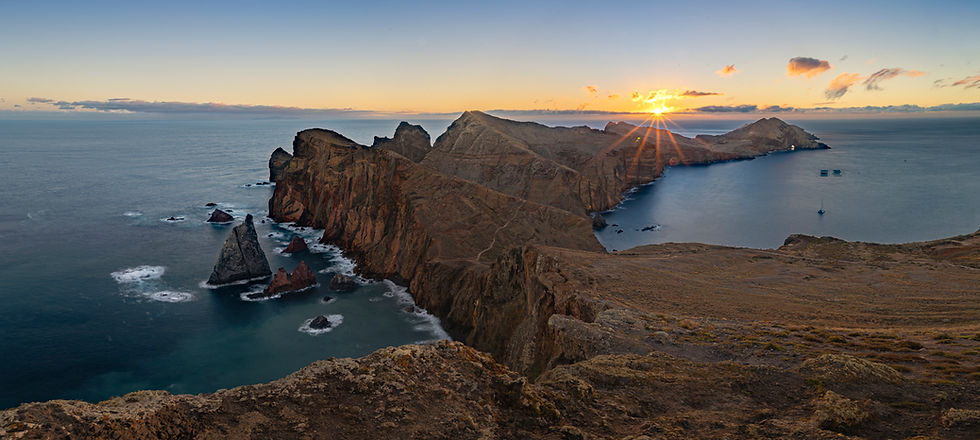 Sunrise over the Ponta de São Lourenço peninsula in Madeira, with a sun star on the horizon behind the cliffs.