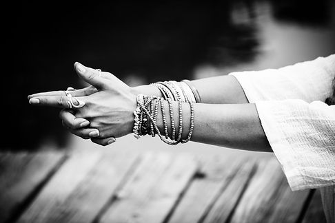 woman hands in yoga symbolic gesture mudra wearing lot of bracelets and rings outdoor clos