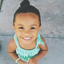 young girl looking up at the camera with a big smile