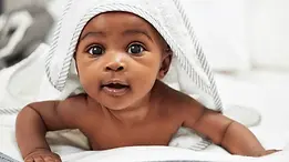 cute black baby with a hooded towel lying on tummy with a cute expression