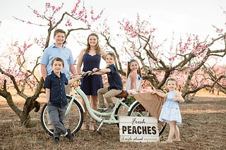 Kalawi Farm grandchildren posing on old fashioned bike in front of the peach trees