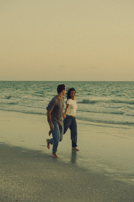 Couple running hand-in-hand on the beach at sunset