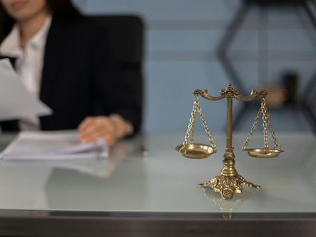 An attorney reviewing financial documents at her desk, with golden scales of justice in the forefront of the shot.