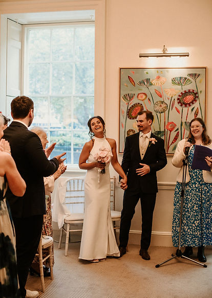 London celebrant Mair Garland and a wedding couple with applauding guests at their wedding in 11 Cavendish Square, London.