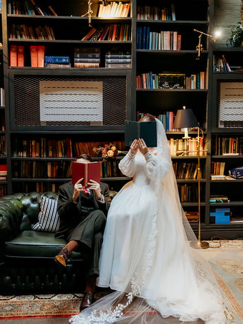 A bride and groom pose behind books and are sitting on a Chesterfield sofa in the library of The Mitre Court hotel in Hampton Court. The ceremony was led by London celebrant Mair Garland.