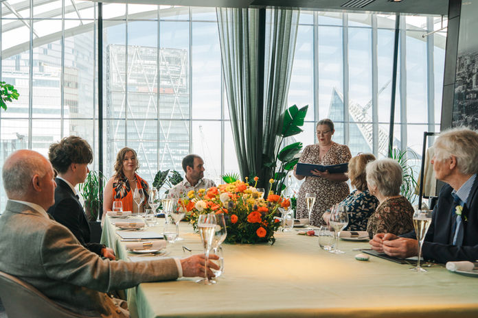 Wedding celebrant London Mair Garland leading a vow renewal ceremony at the Sky Garden, with the couple and their family looking towards her mid-ceremony.