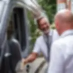 chauffer opening the door of a minibus
