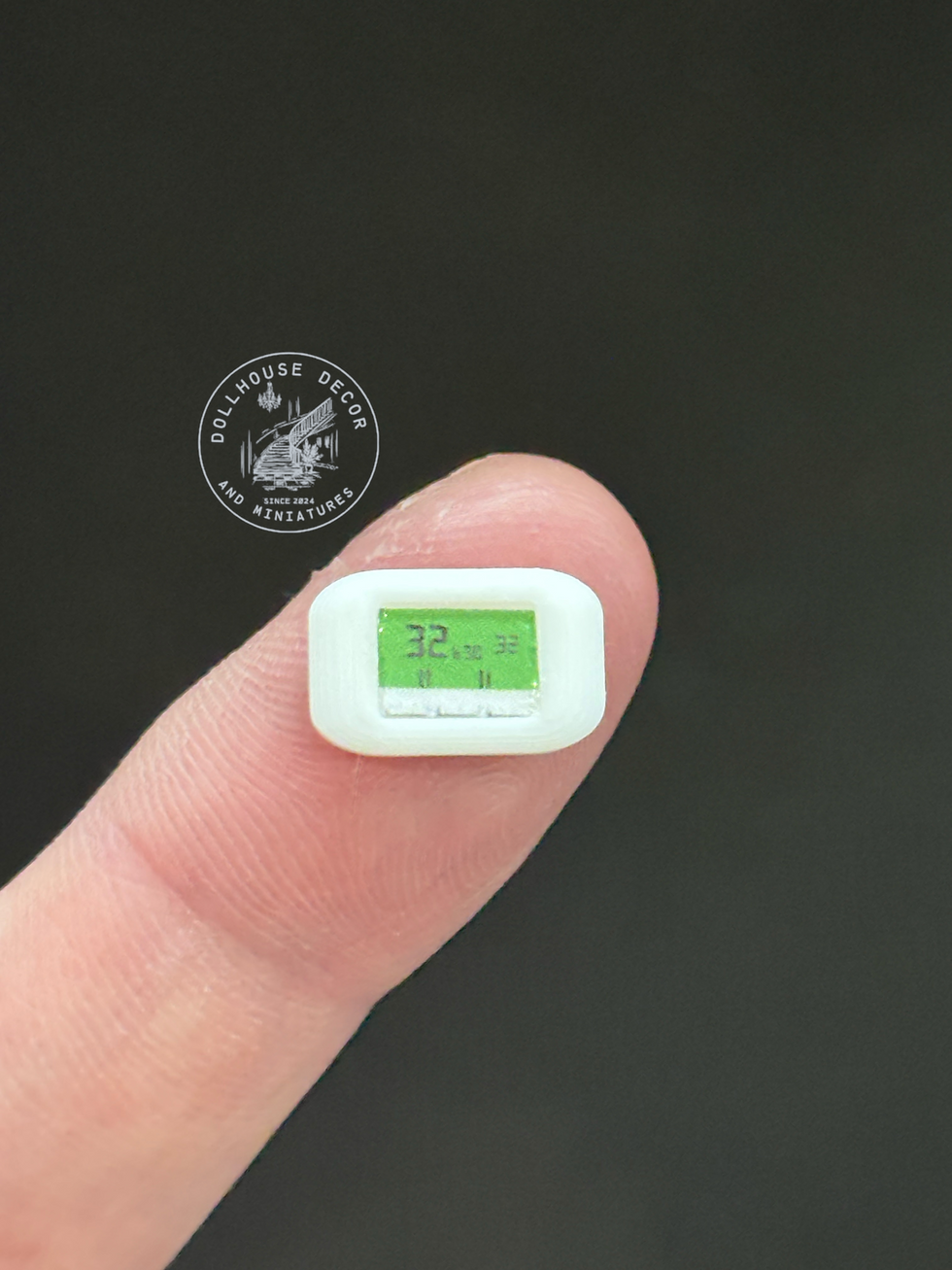 1:12 scale miniature thermostat displayed on a fingertip for size comparison.