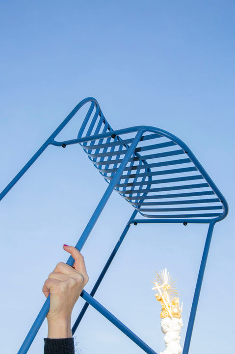 blauer Barhocker aus metall wird in den Himmel gehalten