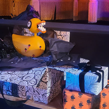 Close-up of a menacing Undead Duck toy with sharp teeth and bullet holes sitting on wrapped gifts from ‘The Nightmare Before Christmas’.