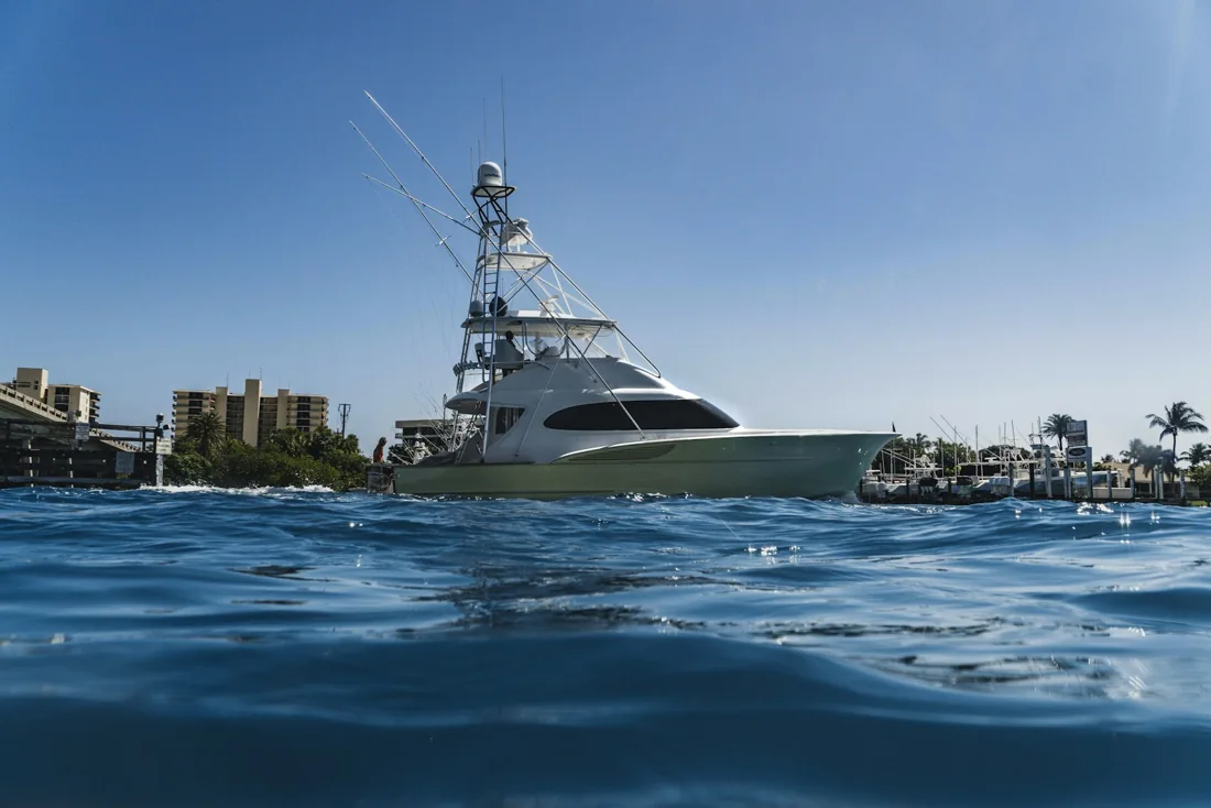 Embarcação de pesca esportiva com torre e suportes de vara vista ao nível da água.