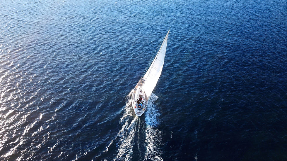 Sailboat on a long ocean passage at sunset with no visible land, representing cruising without Starlink.